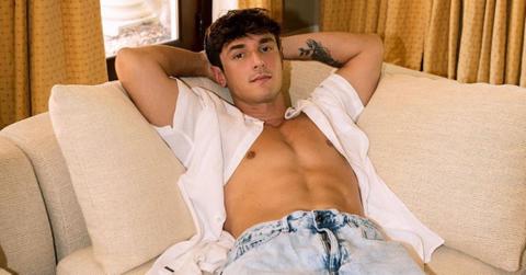 Bryce Hall laying on his couch with his short unbuttoned.