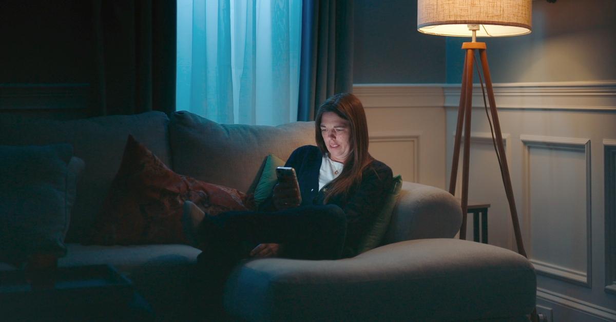 Kendra Licari texts on her phone on a couch.