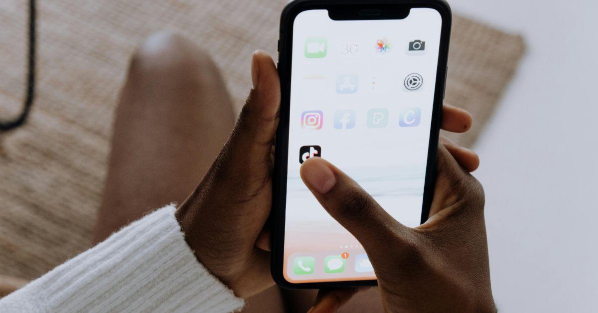 A person clicking the TikTok app on their phone.