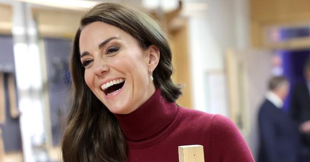 Catherine, Duchess of Cornwall in a red blouse, grins during a visit to the National Maritime Museum Cornwall