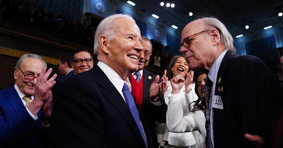 Joe Biden shakes hands with a member of Congress wearing a 153 sticker.