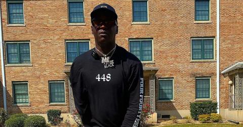 OG Boobie Black wears black and poses in front of Magnolia projects in New Orleans.