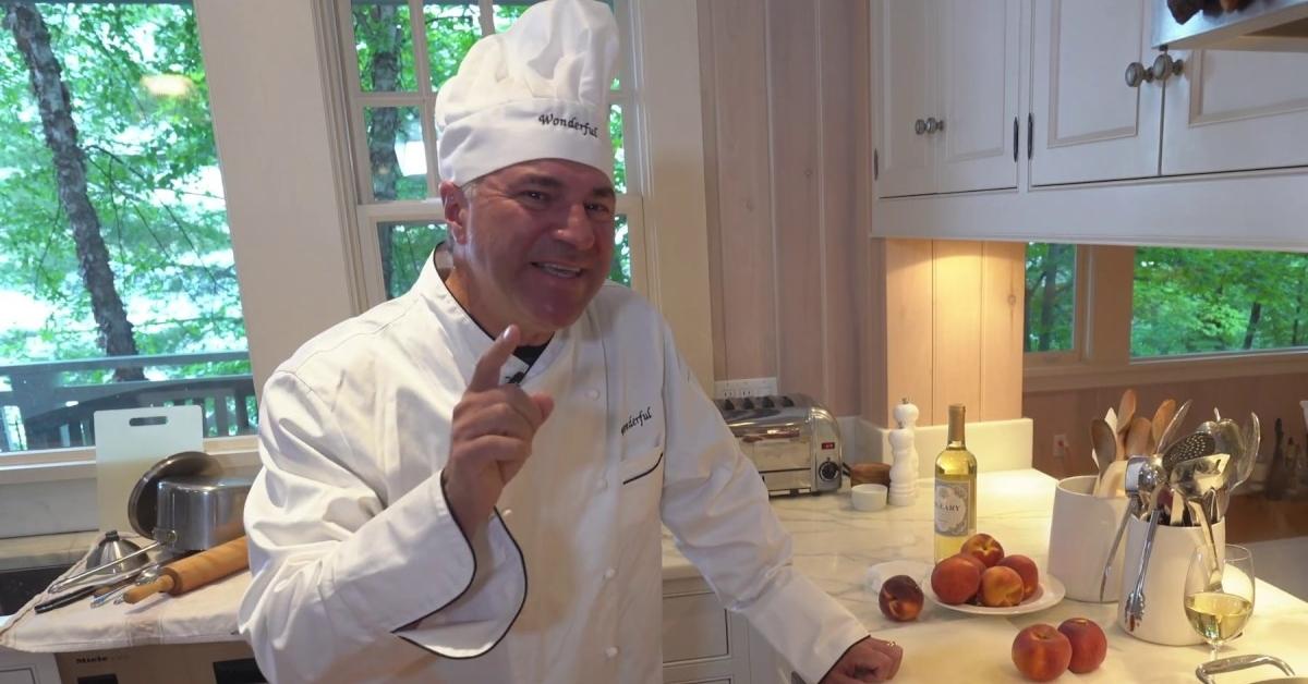 Kevin O'Leary wearing chefs hat and jacket in the kitchen.