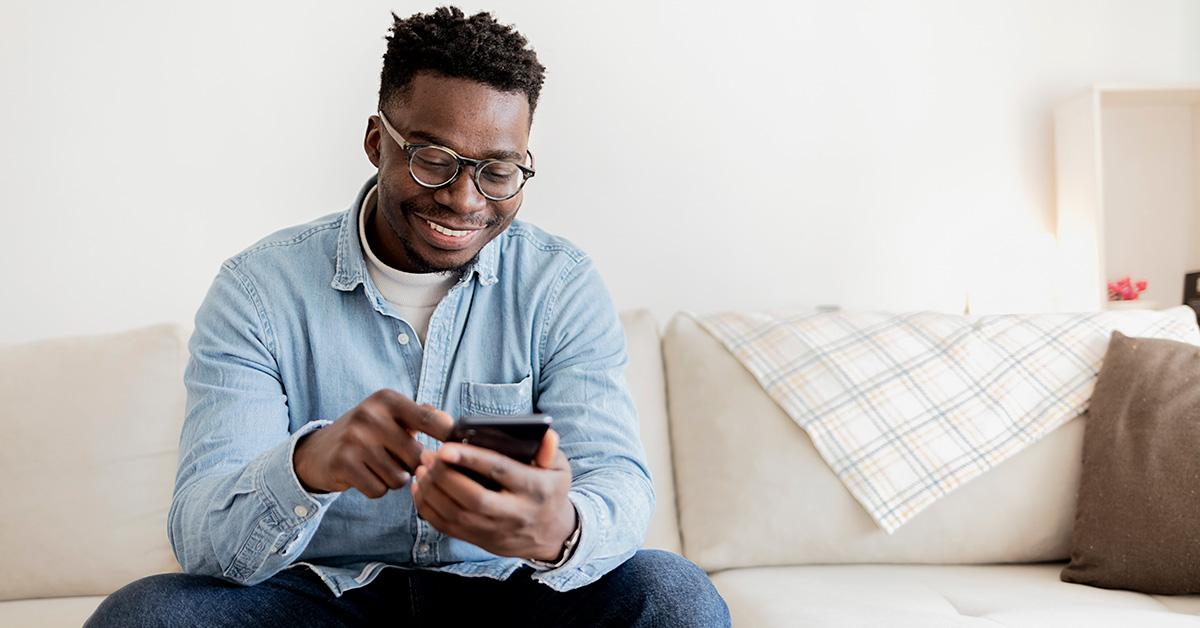 A man smiling and looking at a phone. 