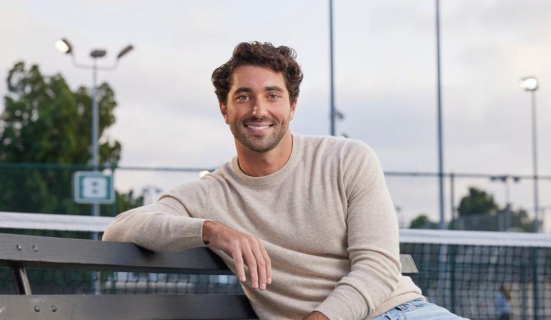 The Bachelor Joey Graziadei sitting on a park bench.