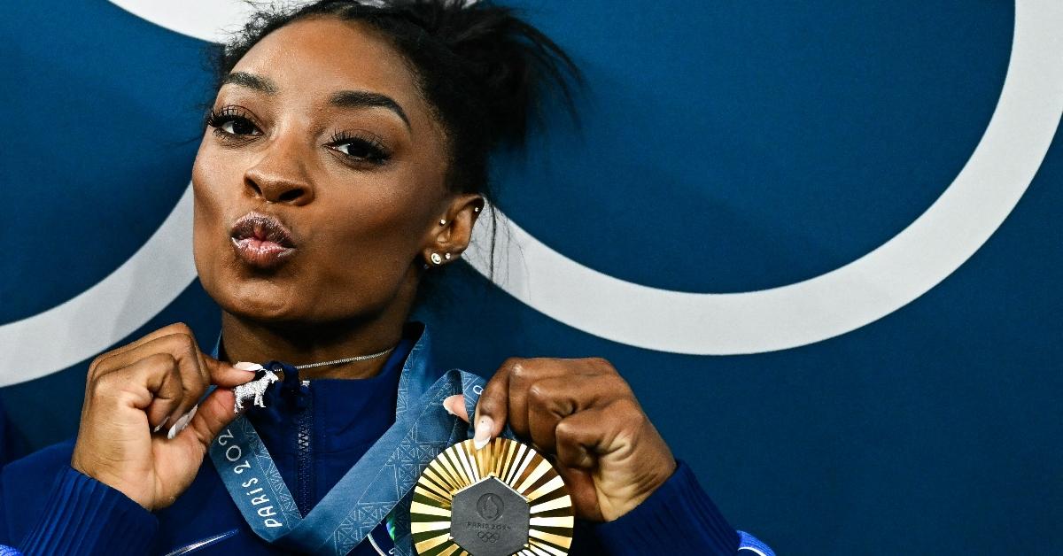 US' Simone Biles poses with her gold medal and a goat necklace after the podium ceremony for the artistic gymnastics women's all around final of the Paris 2024 Olympic Games at the Bercy Arena in Paris, on August 1, 2024. (Photo by Loic VENANCE / AFP) (Photo by LOIC VENANCE/AFP via Getty Images)