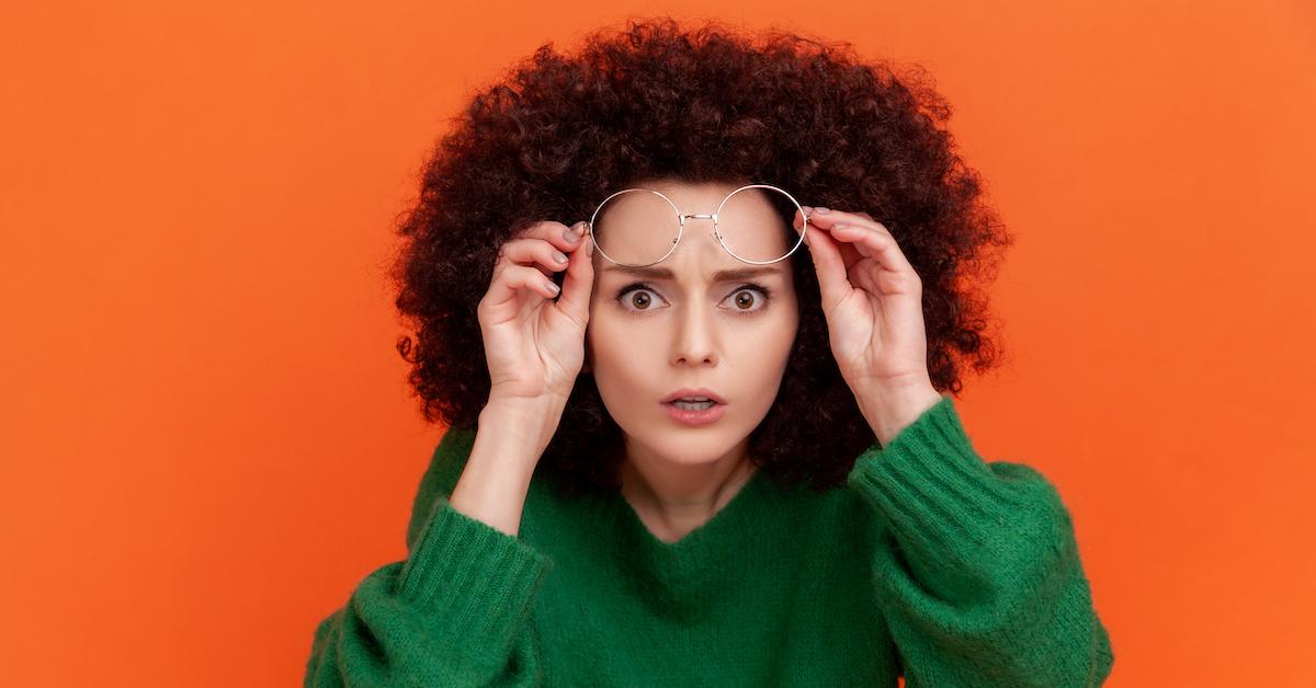 woman lifts up her glasses in disbelief