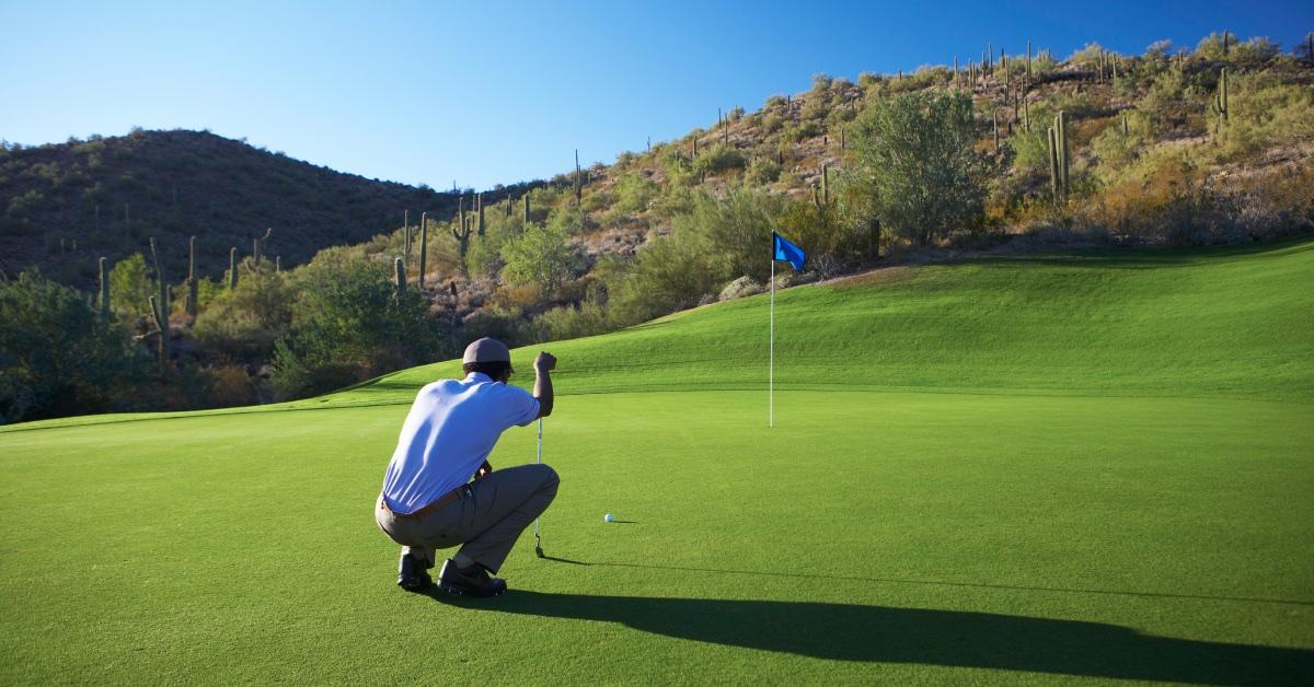 Golfer lining up putt on golf course.