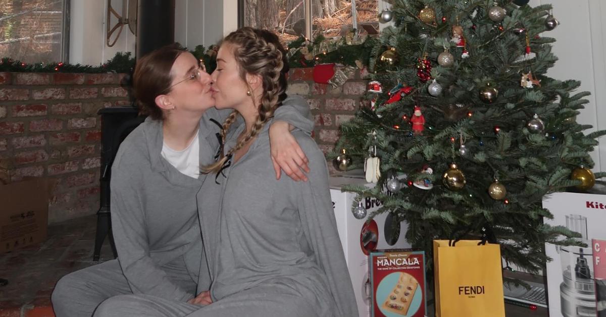 Robby Hoffman and Gabby Windey share a kiss in front of a Christmas tree.