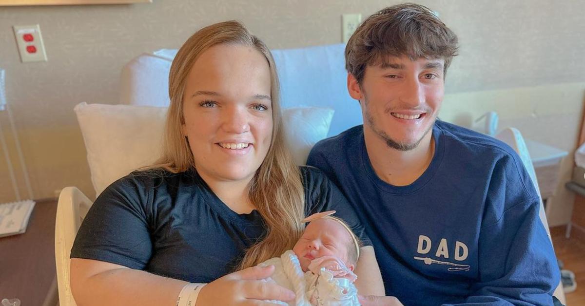 Elizabeth Johnson and Brice Bolden smile and pose in a hospital bed with their daughter, Leighton.