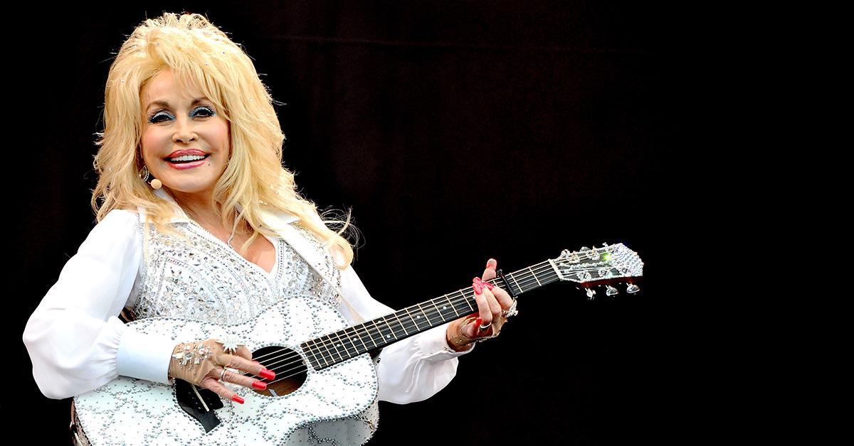 Dolly Parton in white with a white guitar. 