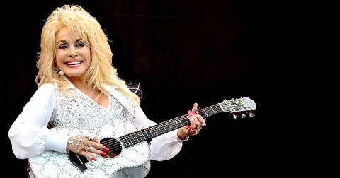 Dolly Parton in white with a white guitar.