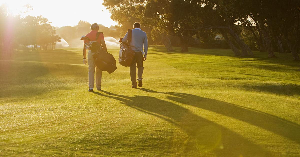 Two golfers walking on a course. 