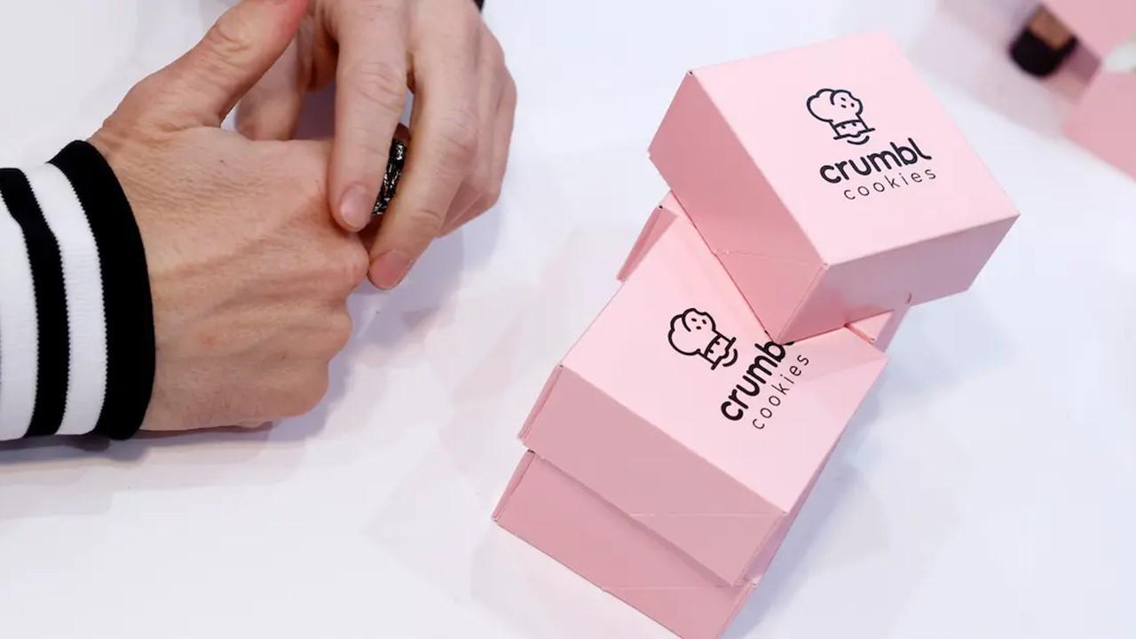 Crumbl Cookies boxes with someone's hands poised nearby