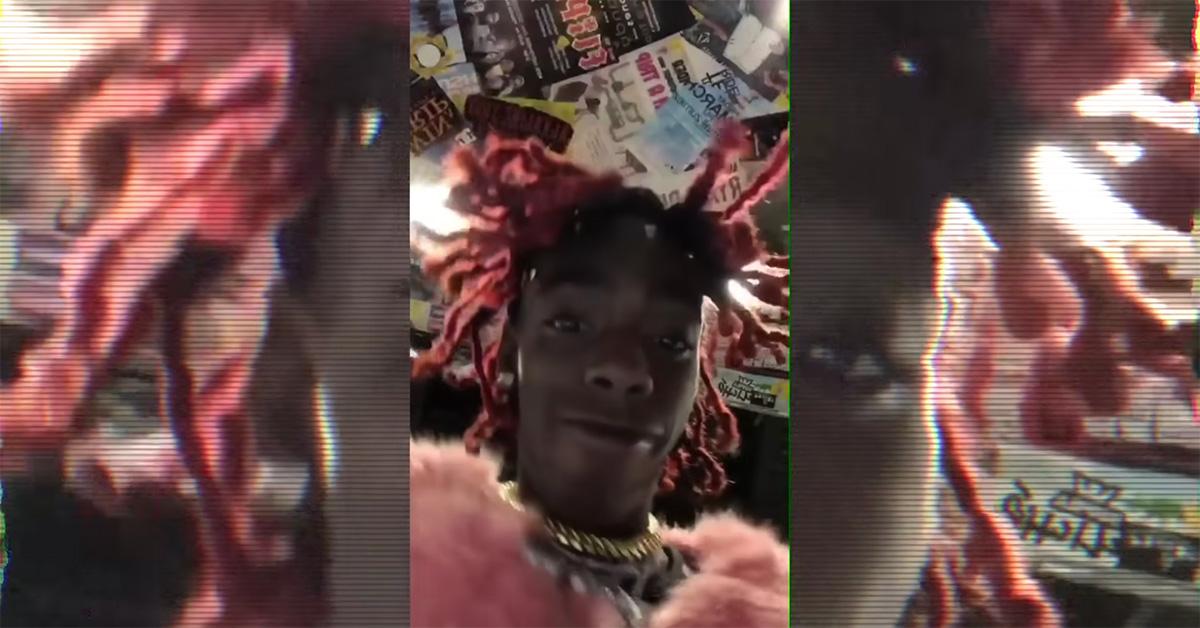 YNW Melly with pink hair looking down at the camera.