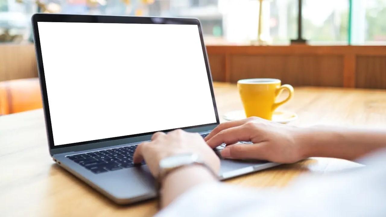 A woman using and working on laptop touchpad with blank white desktop screen