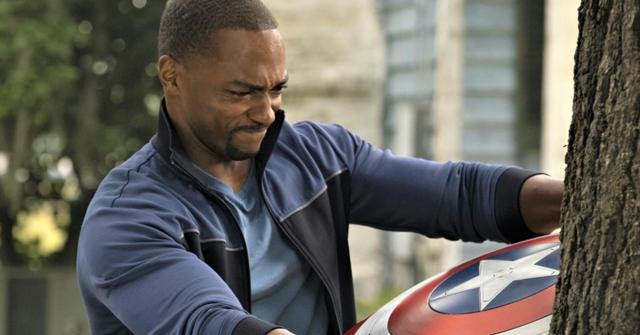 Sam Wilson struggles to pull Captain America's shield out of a tree.