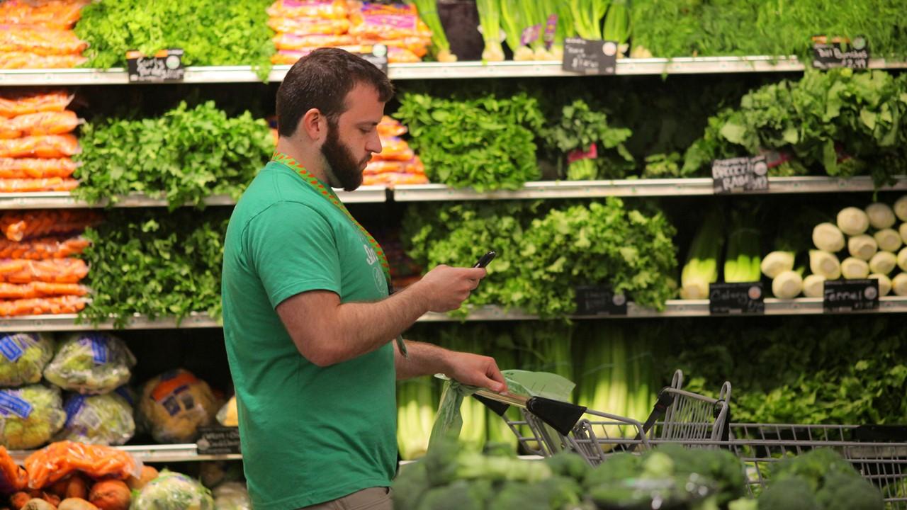 A male Instacart shopper looking at a grocery list on his phone