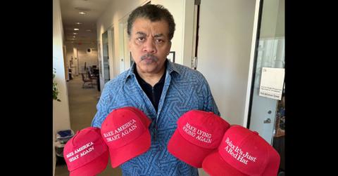 Neil DeGrasse Tyson holding a bunch of red hats.