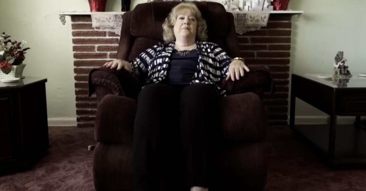 Barbara Mabee Abel sits in her home on a maroon chair 