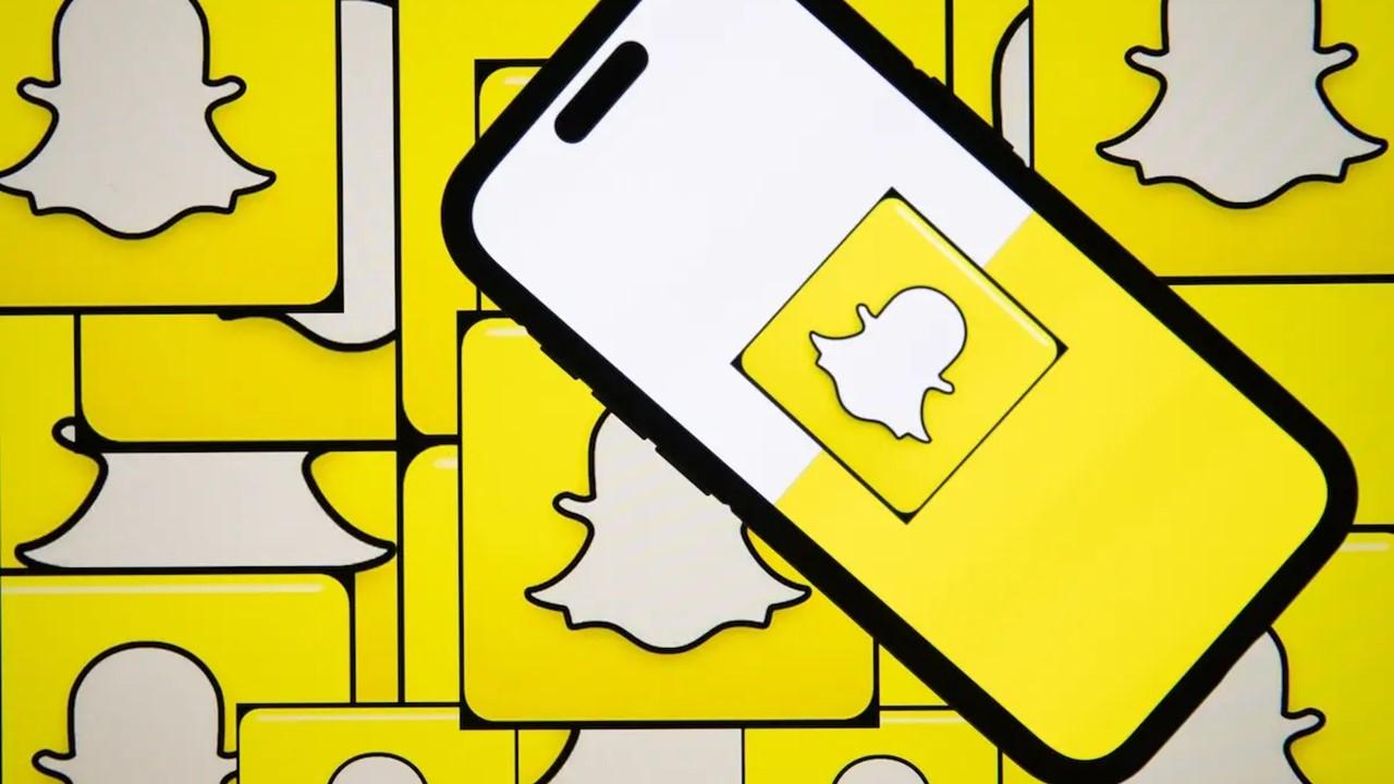 The Snapchat logo on a phone and in the background