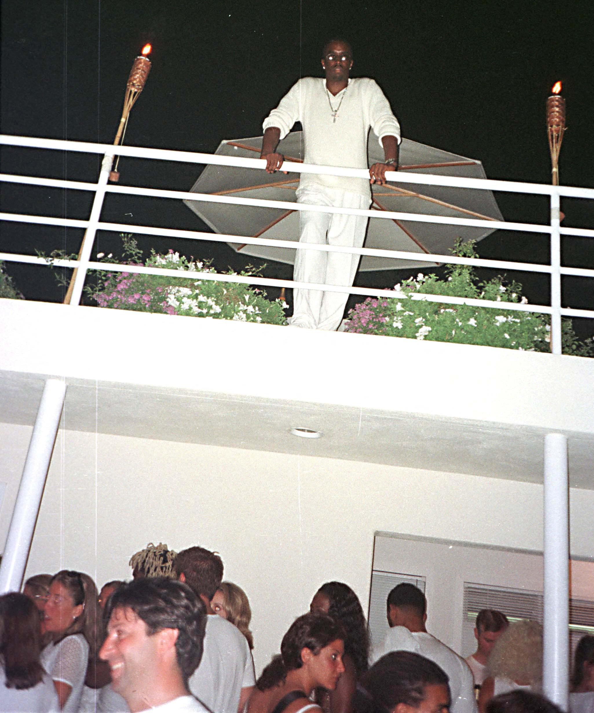 Diddy standing above a crowd of people at his 1999 White Party in the Hamptons.