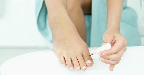 A person painting their toenails white.