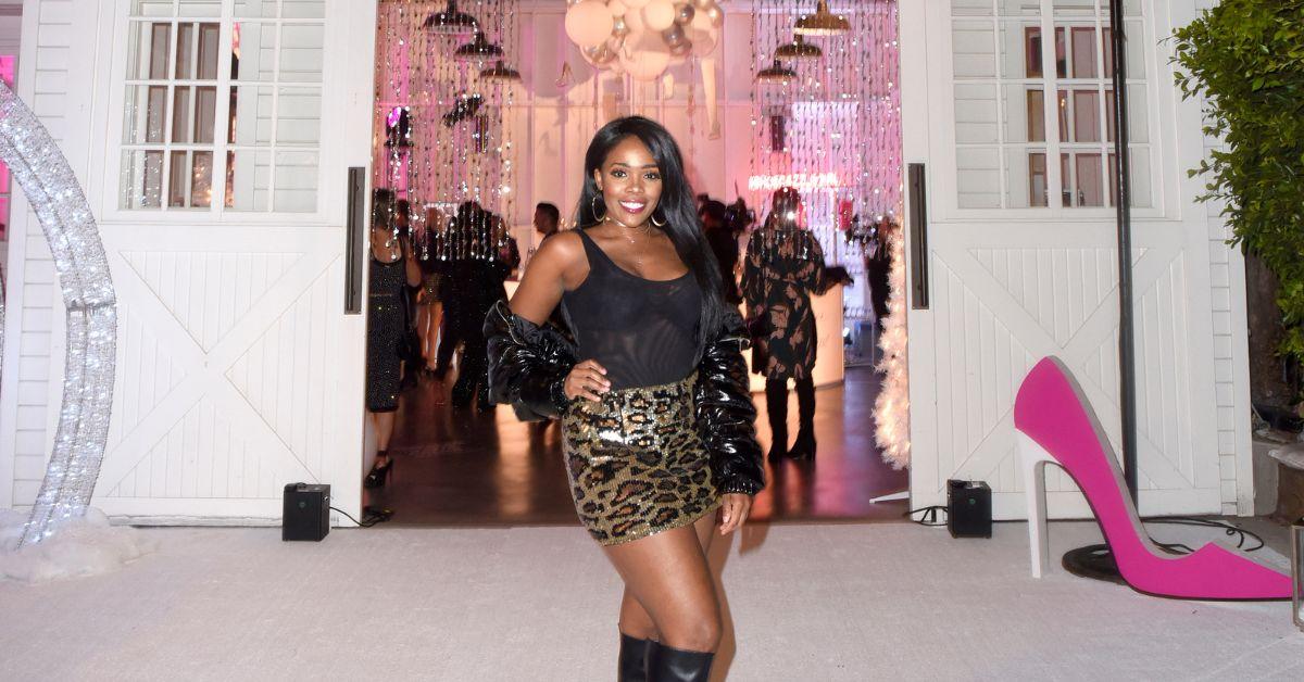 Jasmine Goode posing in front of Erika Jayne's Shoe-Dazzle event