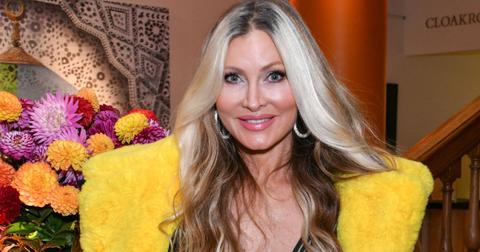 Caprice Bourret poses for a photo in front of flowers at an event