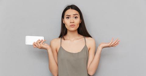 Confused woman holding smartphone