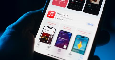 Hand holding a phone with the Apple Music app showing