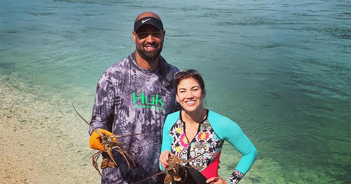 Hope Solo and Jerramy Stevens holding lobsters on the beach. 