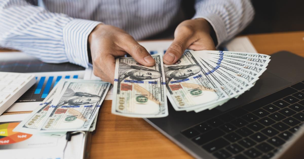 A wealthy person holds several $100 bills.