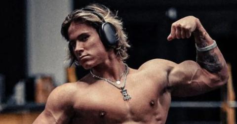 Alex Eubank flexes at the gym while wearing headphones