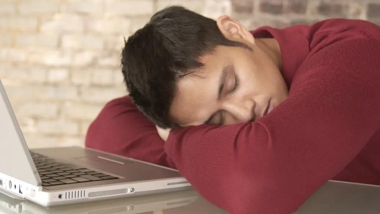 A man asleep by his computer when he's supposed to be working