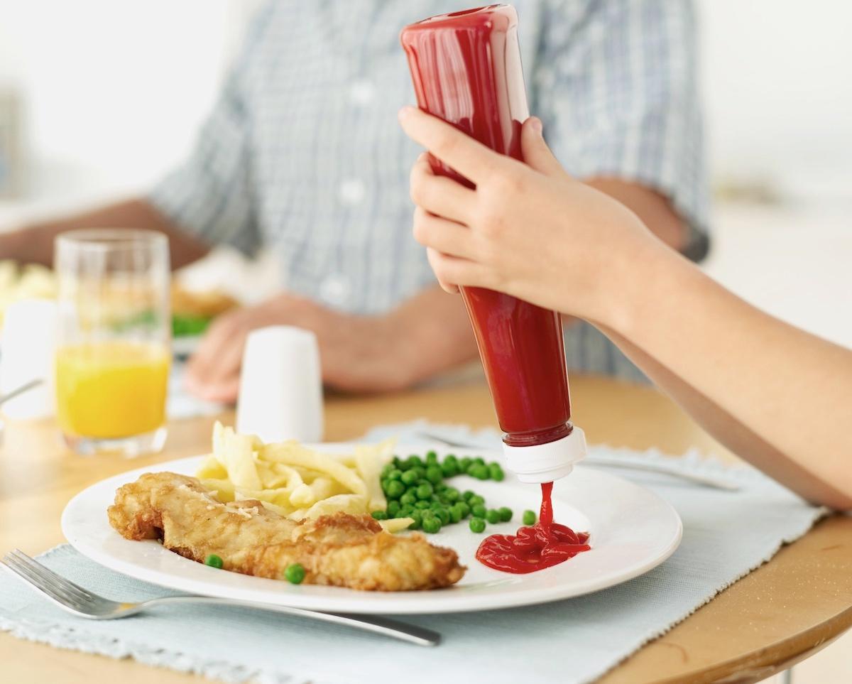 A person squeezing out ketchup