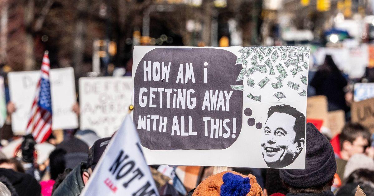 A protest featuring a sign about Elon Musk. 