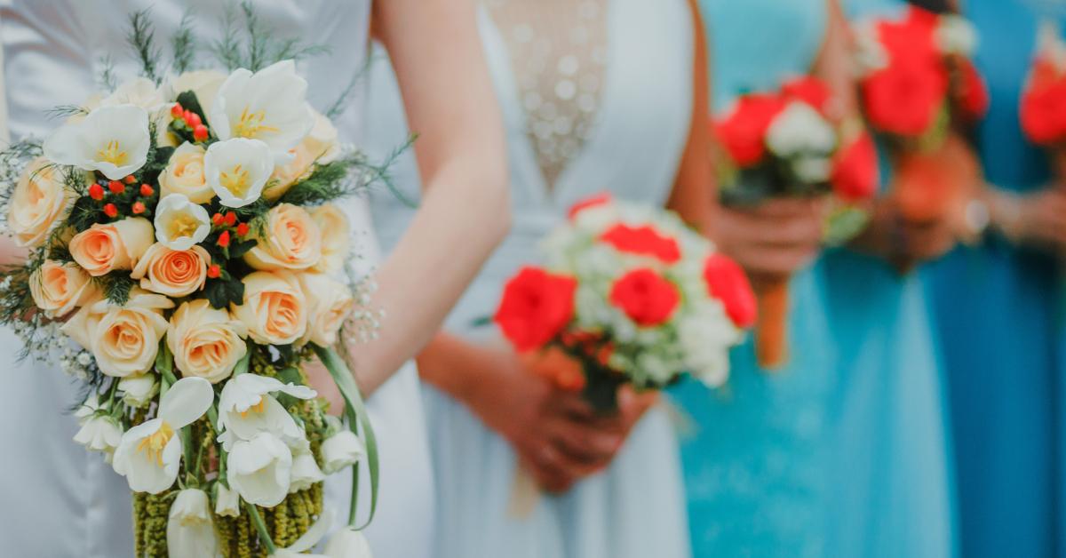 A bride and her bridesmaids, who are all wearing different shades of blue dresses.