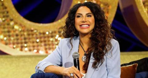 Jennifer Aydin smiles while holding a microphone at BravoCon2023