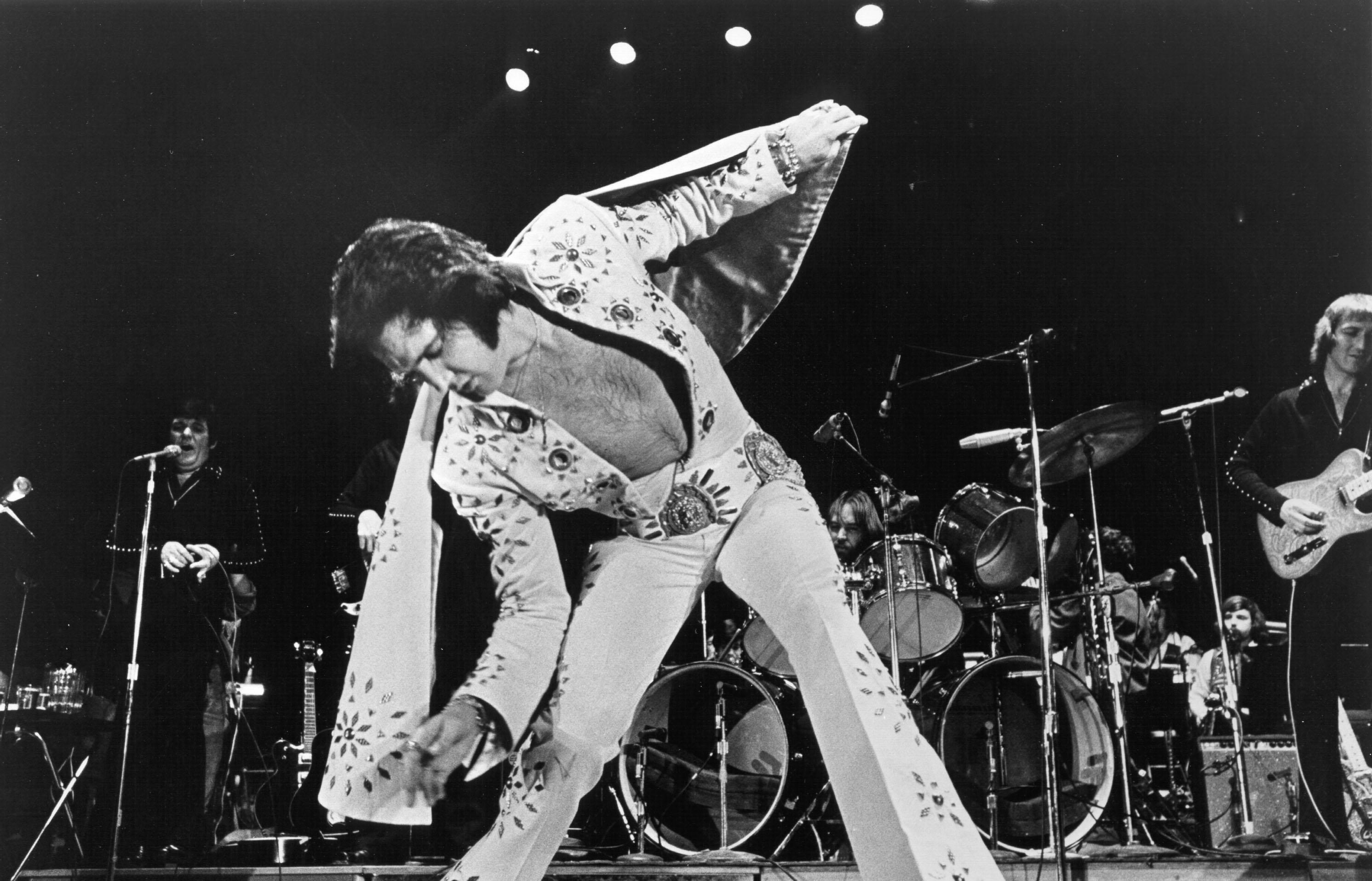 Elvis Presley sporting his iconic rhinestone jumpsuit while performing.