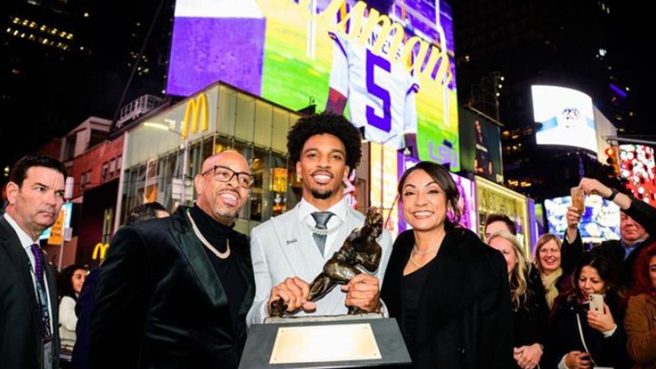 Jayden Daniels holding the Heisman Trophy with his parents