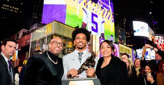 Jayden Daniels holding the Heisman Trophy with his parents