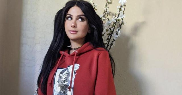 SSSniperWolf standing in front of a pot of flowers.