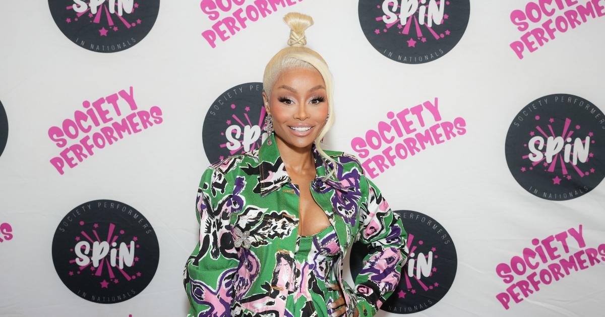 Blac Chyna poses and smiles wearing a matching pink and green top and jacket.