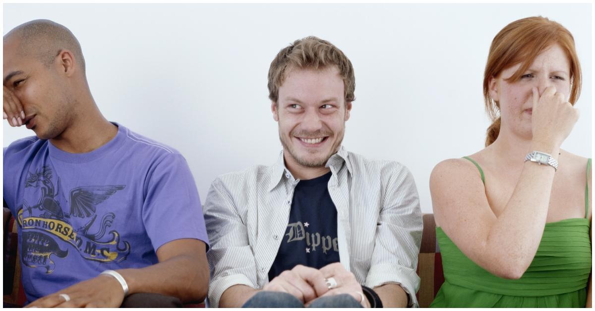 (l-r): man holding nose, another man smiling, a woman holding her nose.