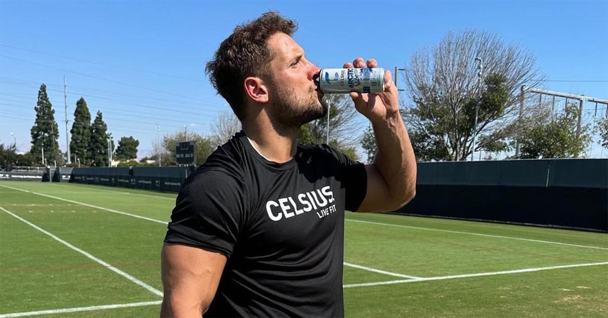 Nick Bosa drinking Celsius on a football field. 