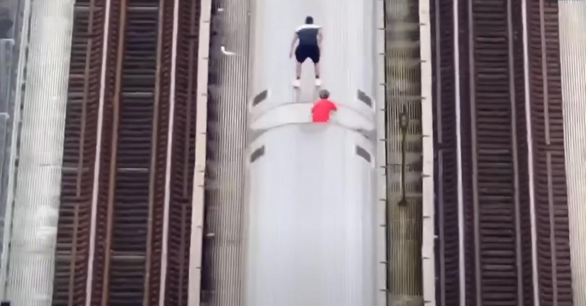 Two people subway surf on top of a New York City Subway train