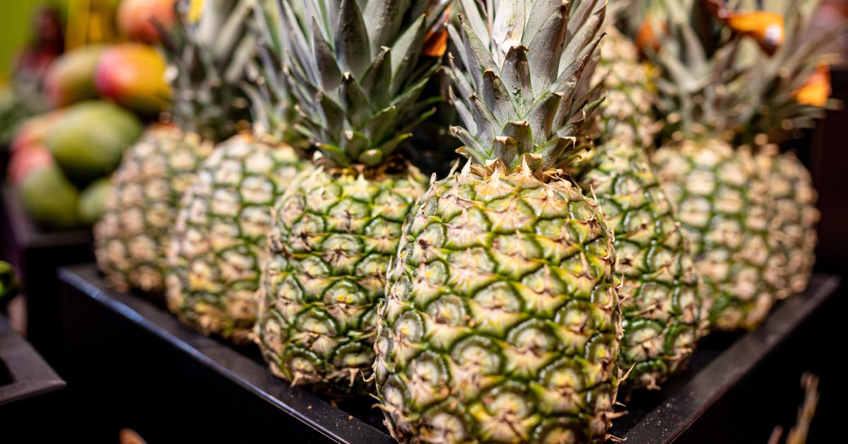 Multiple pineapples lined up in a grocery store.