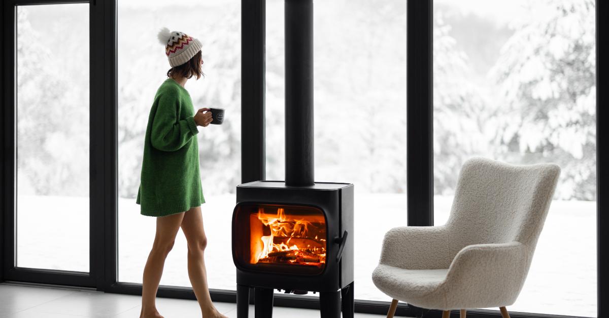 woman near fireplace looks at snow