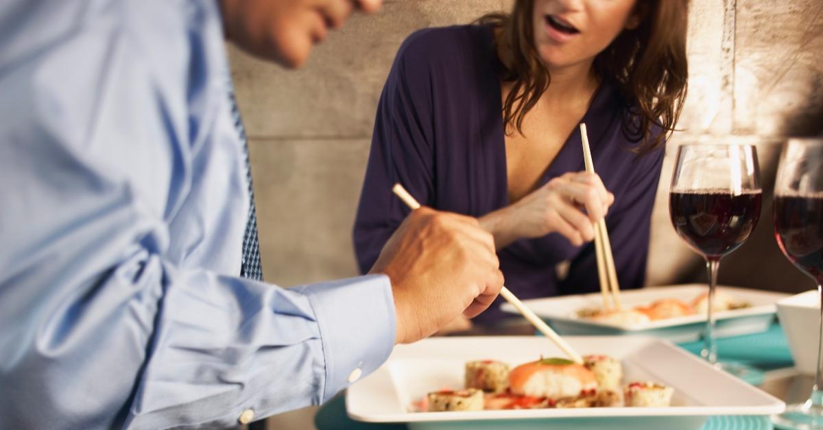 man and woman eat dinner at restaurant with chopsticks and wine